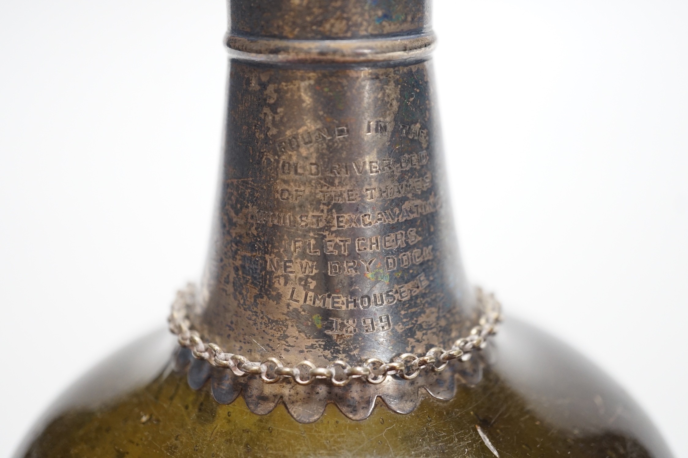 An 18th century green glass onion-shape bottle, with later silver mount, London, 1899, together with a George III silver 'S' decanter label, Phipps & Robinson, London, 1806. 17cm